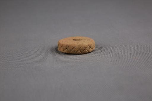 商圆饼形中穿戳印点纹刻划斜线纹夹砂红褐陶纺轮